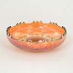 VIDRO, uma (1) antiga fruteira confeccionada em vidro, tonalidade âmbar e irizada, dita Amberina ou Carnival Glass (esta denominação surgiu nos E.U.A. no começo do século XX, para uma infinidade de peças de vidro grosseiro, de tonalidade irisada, com reflexos de dourados que lembram o amarelo âmbar, também nos E.U.A., na década de vinte, eram distribuídas como prêmios em bailes carnavalescos e parques de diversão daí a segunda denominação, várias manufaturas produziram na época este tipo de peça, a americana Sandwich Glass foi a maior fabricante, inclusive a Esberard Antiga fábrica de vidros localizada em São Cristóvão no Rio de Janeiro, fundada no segundo reinado no século XIX por Francisco Antonio Maria Esberard, um dos pioneiros na historia de vidros no Brasil, fez muitas peças principalmente compoteiras), modelagem em geométricos, palmas e flores, borda recortada, medindo 24,5 cm diâmetro, vide foto.