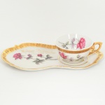 PORCELANA, uma (1) xícara de chá, pires com aba para petiscos, ornamentação policromada representando rosas, marca possessória gravada a ouro, além de generosos arremates a ouro, marca P II RJ (D. PEDRO II, Rio de Janeiro, RJ, fundada em 1921 por Tinoco Machado, Industrial Carioca, que contava com auxiliares que vieram da tradicional Fábrica de Vista Alegre de Portugal, foi a primeira fábrica de porcelana autêntica em escala Industrial no Brasil, funcionou até a década de 80), medindo o pires 25 cm comprimento, ideal para coleção de cristaleira, vide foto.