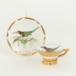 PORCELANA, uma (1) xícara com ornamentação policromada pintada a mão representando tucano pousado no galho e beija flor, generosos arremates a ouro, atelier de decoração GE WI Ltda., ideal para coleção de cristaleira, vide foto.