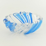CRISTAL, um (1) cinzeiro com modelagem espiralada, grosso, incolor e translúcido, detalhes na tonalidade azul, medindo 17,5 cm diâmetro e 6,5 cm altura, sinais de uso, vide foto.