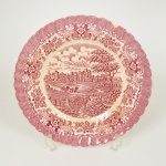 FAIANÇA INGLESA, um (1) medalhão decorativo representando paisagem com castelo, figuras, cachorro, etc., borda com barrado em flores e volutas, lascado na borda, craquejado característico do envelhecimento de toda a faiança, marca HOSTESS TABLEWARE (tradição desde 1884), modelo OLDE COUNTRY CASTLES, made in England, medindo 27 cm diâmetro, tonalidade magenta, vide foto.