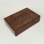 DIVERSOS, uma (1) caixa com dispositivo musical funcionando, tampa com ornamentação em marchetaria geometrizada e couro pirografado, faltam dois pés, medindo 25 x 17 x 7 cm, sinais de uso, vide foto.