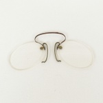 INSTRUMENTO ÓPTICO, um (1) antigo óculos Pince-nez ou Pincenê (muito popular na transição dos séculos XIX/XX, porém já eram usados no século XIV, o nome vem do francês pincer beliscar e nez nariz, sem hastes e sustentados apertando o nariz, as vezes confundido com lorgnon, óculos de uma só haste lateral para ser segurada com a mão), monture em metal, com sinais de oxidação, medindo 9 cm comprimento, sinais de uso, vide foto.