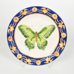 FAIANÇA, um (1) medalhão decorativo pintado a mão representando borboleta, borda com barrado vegetalista, policromado, sem marca de manufatura aparente, medindo 27 cm diâmetro, vide foto.