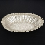 METAL PRATEADO, uma (1) fruteira oval com borda recortada e vazada, fundo e lateral relevados em flores e folhas, sem marca de manufatura aparente, medindo 29,5 x 21,5 x 4,5 cm, sinais de uso, vide foto.