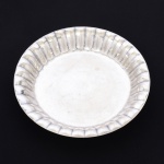 METAL PRATEADO, uma (1) travessa circular de borda alta e canelada, marca EBERLE (Abramo Eberle 1880, Monte Magrè 1945, Caxias do Sul, veio com uma das primeiras levas de imigrantes italianos para o Brasil em 1884 junto com seus pais Giuzeppe Eberle e Luigia Zanrosso, seu pai abriu uma pequena funilaria mas como tinha que trabalhar na lavoura quem cuidava era a mãe e o pequeno Abramo ajudava na funilaria; em 1896 quando o pai resolveu vender a funilaria para concentrar os esforços da família na lavoura Abramo, com 16 anos de idade, se propôs a comprá-la do pai, em 1918 já com o nome Abramo Eberle & Cia iniciou a fabricação de talheres e utensílios de mesa, morreu em 1945 com 65 anos de idade e os filhos deram continuidade aos negócios até 1984 quando venderam para o Grupo Zivi), medindo 26,5 cm diâmetro, sinais de uso, vide foto.