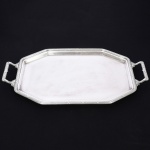 METAL PRATEADO, uma (1) bandeja octogonal com ornamentação no padrão Império Napoleônico com frisos intercalados por X e folhas, alças na mesma padronização, marca FRACALANZA (tradição desde 1884), medindo 48 x 33 cm mais as alças, sinais de uso, vide foto.
