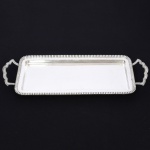 METAL PRATEADO, uma (1) bandeja retangular com borda reforçada e canelada, alças no mesmo padrão, marca MERIDIONAL, espessada a prata na técnica E.P.S. (electro plate silver), medindo 38 x 18,5 cm, sinais de uso, vide foto.