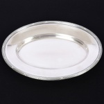 METAL PRATEADO, uma (1) travessa oval, ornamentação no padrão Império Napoleônico com frisos intercalados por X, marca FRACALANZA (tradição desde 1884), medindo 32 x 22 cm, sinais de uso, vide foto.