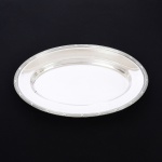 METAL PRATEADO, uma (1) travessa oval, marca FRACALANZA (tradição desde 1884), ornamentação relevada no padrão Império Napoleônico com frisos intercalados por X, medindo 36 x 24 cm, sinais de uso, vide foto.