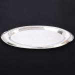 AÇO INOX, uma (1) travessa oval oblonga, borda sinuosa, marca GAZOLA (Indústria Metalúrgica Gazola S/A, fundada em 1932 por José Gazola, no Rio Grande do Sul, RS, fechou em 2009, usou a marca fantasia ELMO na década de 50), medindo 53 x 22 cm, sinais de uso, vide foto.