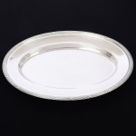 METAL PRATEADO, uma (1) travessa oval, marca FRACALANZA (tradição desde 1884), ornamentação relevada no padrão Império Napoleônico com frisos intercalados por X, medindo 41 x 27 cm, sinais de uso, vide foto.
