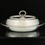 METAL PRATEADO, uma (1) travessa oval com tampa, adaptável para duas travessas, marca FRACALANZA (tradição desde 1884), ornamentação relevada no padrão Império Napoleônico com frisos intercalados por X, medindo 30,5 x 23 cm, sinais de uso, vide foto.