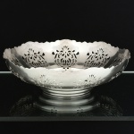 METAL PRATEADO, uma (1) fruteira circular com borda recortada e vazada em elementos vegetalistas, fundo em degraus, sem marca de manufatura aparente, medindo 27 cm diâmetro e 8 cm altura, sinais de uso, vide foto.
