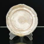 METAL PRATEADO, uma (1) fruteira miniatura de pé baixo, borda plissada e relevada em corda, base cônica e canelada, marca parcialmente legível, não identificada, medindo 14 cm diâmetro e 3 cm altura, vide foto.