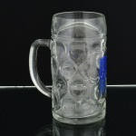 VIDRO, uma (1) caneca, grossa, incolor e translúcida, modelada em esferas, propaganda esmaltada da J. W. AUGUSTINER BRÄU MÜNCHEN GEGRÜNDET 1328, ideal para coleção de bar, capacidade 0,5 litro, medindo 16 cm altura, sinais de uso, vide foto.
