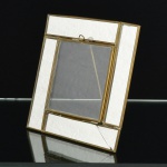 FOTOGRAFIA, um (1) porta-retratos confeccionado em vidro, moldura com espelhos, um deles trincado, monture em latão, medindo 14,5 x 14,5 cm, vide foto.