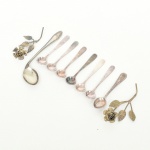 ESCULTURAS E TALHERES, um (1) saco com vários itens, confeccionados em metal prateado: 2 esculturas decorativas representando rosas; 1 colher para criança aprender a comer e diversas colheres e conchas variadas para café e sal, sinais de uso, vide foto.