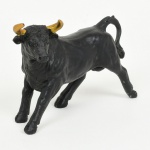 ESCULTURA, uma (1) animalista representando touro, confeccionada em material sintético na tonalidade pretacom chifres dourados, medindo 10,5 cm comprimento, vide foto.