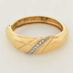 BIJUTERIA DE GRIFE, um (1) bracelete, marcado VALENTINO (Valentino Clemente Ludovico Garavani, 1932,Voghera, Lombardia; 2026, Lácio, Roma, estilista italiano, ingressou no mundo da moda na década de 50),confeccionado em metal dourado e strass, medindo 7 x 6 cm, vide foto.