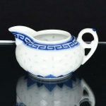 PORCELANA, uma (1) molheira ornada no padrão dito grão de arroz (denominação dada as peças em porcelanaque, após minuciosamente entalhadas com estilete, são embebidas diversas vezes em barbotina, antes da queima, paradar este efeito),ornada com barrado geométrico e vegetalista, marcada em caracteres na base, medindo 11 cm diâmetromais alça e bico, sinais de uso, vide foto.