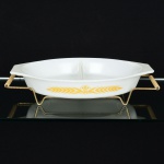 VIDRO OPALINADO, uma (1) travessa oval com divisória, branca leitosa dita milk glass, barrado esmaltado emelementos vegetalistas na tonalidade amarela, marca PYREX, made in USA, medindo 32 x 21,5 cm, acompanha suporteem aramado vergado com alças em polímero, medindo 4 x 11 cm, vide foto.