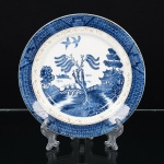 FAIANÇA JAPONESA, um (1) prato decorativo com ornamentação dita WILLON (Segundo a lenda chinesa: Umcerto Mandarim tinha uma leal e devotada filha, possuidora de rara beleza. Certo dia, em que descobre que ela estavaapaixonada por um carteiro que lhe fazia a corte, e que era por ela correspondida, expulsa a filha de casa e roga-lhe umapraga: que ao ser trocado o primeiro beijo pelo casal, eles se transformariam em dois pombos), também conhecida comopombinhos, tonalidade azul sobre fundo branco, borda com barrado geometrizado, arremates a ouro já com sinais dedesgastes, sinais de restauro visto principalmente no verso, marca Imperial Ironstone Ware N.K.T, made in Japan,medindo 22 cm diâmetro, vide foto.