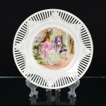 PORCELANA, um (1) antigo prato decorativo, parte central ornada com cena de galanteio em policromia, bordavazada, arremates a ouro já com sinais de desgastes, sem marca de manufatura aparente, possivelmente de procedênciaAustríaca, medindo 21,5 cm diâmetro, vide foto.