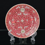 PORCELANA CHINESA, um (1) prato decorativo com ornamentação policromada, fundo na tonalidade magenta,com nuvens, flores e morcegos em policromia, além de caracteres, medindo 18 cm diâmetro, marca de origem emlegenda e caracteres no verso, vide foto.
