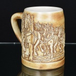 PORCELANA, uma (1) caneca com propaganda da BUDWEISER, ornamentação relevada com carroça puxadapor quatro parelhas de cavalos, medindo 12 cm altura, sem marca de manufatura aparente, ideal para coleção de bar,vide foto.