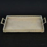 METAL PRATEADO, uma (1) bandeja retangular, borda em gradil vazado, alças cilíndricas e vazadas, pés embolacha, sem marca de manufatura aparente, medindo 41 x 31 cm mais as alças, sinais de uso, vide foto.