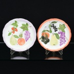 PORCELANA, dois (2) pratos decorativos, com ornamentações distintas e policromadas, pintadas a mão peloatelier MR, representando frutas, marca INTER-AMERICAN (Los Angeles, Califórnia, USA, 1965 a 1978, empresacriada pelo Grupo Schmidt com a finalidade de distribuição da porcelana brasileira no mercado norte americano ecanadense), medindo 19 cm diâmetro, vide foto.