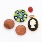 GEMAS E OUTROS, cinco (5) itens: 2 (par) cabochões de pedra do sol; 1 pingente camafeu representando bustofeminino perfilado, monture em metal dourado; 1 cabochão em pedra avermelhada; 1 disco em vidro de Murano ditoMille Fiori, vide foto.