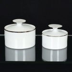 PORCELANA, dois (2) açucareiros de tamanhos distintos, clássicos, tonalidade branca, arremates com frisosprateados, linha MEDAILLON, manufatura RENNER (Porto Alegre, RS, fundada em 1942; em 1998 foi vendida para aVista Alegre de Portugal; em 1999 mudou a razão social para Vista Alegre do Brasil), medindo o maior 9 cm altura, videfoto.