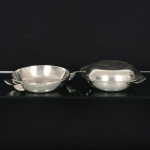 AÇO INOX, três (3) travessas circulares com alça: 1 da marca BELLINI, medindo 23 cm diâmetro; 2 da marcaMERIDIONAL, sendo uma delas podendo servir de tampa, medindo 23 cm e 21,5 cm diâmetro, todas com sinais deuso, vide foto.