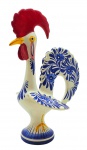Escultura representando o tradicional Galo de Barcelos, em multicolorida cerâmica esmaltada portuguesa. Marca de manufatura não identificada no fundo. Medidas: 39 x 25 cm. Ínfimo bicado na parte inferior de uma das asas.