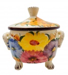Terrina decorada com coloridos padrões florais sobre fundo na cor marfim; no formato circular, com alças laterais retangulares e base com quatro pés; em cerâmica esmaltada, pintada à mão; marca da manufatura (não identificada) e numeração na base. Medidas: 20 x 21 cm.