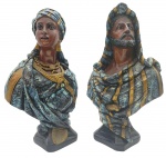 Esculturas representando os bustos de um casal de beduínos, com olhos de vidro e em trajes tradicionais; sobre base quadrada; em gesso policromado. Medidas: 41 x 25 cm. Com ínfimos bicados e descascados na pintura.
