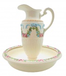 WEISS - Belíssimo gomil adornado com coloridos laços e guirlandas florais; alça da jarra moldada em forma de voluta, e base pedestal com detalhes fitomórficos; bacia decorada na borda com colorida faixa floral; em porcelana pintada à mão, da manufatura brasileira Weiss. Medidas: 41 x 38 cm. Borda da bacia com fio de cabelo.