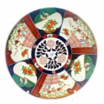 Belíssimo medalhão de porcelana decorado à mão com temática oriental, com coloridos motivos florais, vegetalistas, desenhos geométricos, orgânicos, e detalhes em dourado na frente, e padrões fitomórficos em azul cobalto no verso. Medidas: 41 cm (diâm.). Com ínfimo bicado na borda.