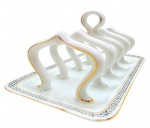 Porta-torradas em porcelana alemã, adornado com filetes dourados e detalhes geométricos na borda da bandeja. Numerado na base. Medidas: 20 x 12 x 10 cm.