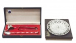 REGÊNCIA PRATA 90 / BELLINI - 02 diferentes itens em metal espessurado à prata, sendo: uma petisqueira com motivos geométricos vazados no metal (borda da bandeja) e bowl em cristal alemão adornado com detalhes radiais elípticos em relevo, em caixa original da marca Regência; e um conjunto para drinks, composto por um pegador de gelo, uma colher bailarina e um dosador, em estojo original da marca Bellini. Medidas: 18 x 3 cm; 29 x 13 x 4 cm (estojo Bellini).