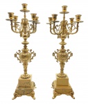Par de candelabros de mesa, no estilo Rococó, com cinco nichos para velas cada e braços em forma de volutas; em bronze ricamente cinzelado com padrões fitomórficos em relevo; sobre base quadrangular escalonada e em resina simulando mármore; apoiado em quatro pés de metal  adornados com volutas e folhagens. Medidas: 51 x 21 cm. Recebeu acabamento em textura metálica dourada.