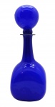OPALINA - Garrafa com tampa de formato globular, pescoço alongado e cilíndrico, e corpo de formato cúbico; na cor azul royal com interior na cor branca. Medidas: 32 x 12 cm. Com trincado na lateral do corpo e bicados no fundo.