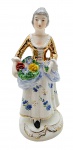 VIEIRA DE CASTRO RIO - Antigo bibelô com a representação de uma figura feminina em trajes de época segurando um buquê de flores; em porcelana multicolorida e com detalhes em dourado. Medidas: 19 x 8 cm. Pescoço com sinais de restauro.