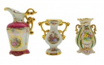 03 diferentes itens em porcelana, sendo: 01 ânfora em porcelana Saler adornada com coloridos motivos florais na base; 01 ânfora adornada com listras verdes e douradas e coloridas flores em biscuit; e 01 jarra com detalhes na cor cereja, colorida cena galante em sua galeria central e acabamento perolizado; todos os itens com alças com douração total e em forma de volutas. Medidas: 15 x 11 cm; 12 x 11 cm; 11 x 8 cm.