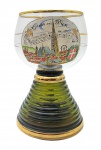 Rara e antiga taça musical souvenir no estilo Römer, com caixa de música acoplada na base; bojo em vidro translúcido com borda decorada com filete dourado, adornado em sua galeria central em esmalte policromado com a inscrição Gruss aus Wien (Saudações de Viena), partitura musical e vista panorâmica da cidade de Viena; base cônica anelada em vidro verde. Origem: Áustria. Nota: Tradicionalmente, o mecanismo musical reproduz a mesma canção gravada na partitura. Medidas: 14 x 10 cm. Mecanismo da caixa de música necessita reparos (inoperante). Douração com desgaste em ínfimos pontos.