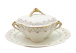 J & M B, LIMOGES, FRANCE - Parte de serviço de jantar composto por 01 terrina e 01 travessa oval, adornadas com coloridas guirlandas florais e douração na pega da tampa e alças laterais da terrina. Em porcelana francesa de Limoges. Medidas: 30 x 17 cm (terrina); 36 x 28 cm (travessa). Douração desvanecida na pega da tampa e alças laterais da terrina, e em alguns pontos dos filetes dourados.