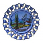 ALCOBAÇA PORTUGAL HAND PAINTED - Medalhão em cerâmica esmaltada portuguesa, moldado com detalhes ondulados e orgânicos vazados na borda, decorado à mão com coloridos padrões fitomórficos e cenário pastoril em sua galeria central. Numerado. Medidas: 36 cm (diâm.).
