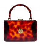 Antiga bolsa retangular feminina, estruturada em plástico rígido no estilo tartaruga (corpo e alças) e ferragens em metal cromado dourado; decorada no centro, em ambos os lados, com detalhe circular em metal dourado adornado com motivos florais e vegetalistas em relevo. Medidas: 28 x 25 x 6 cm. Ferragens com ínfimos desgastes no cromado.